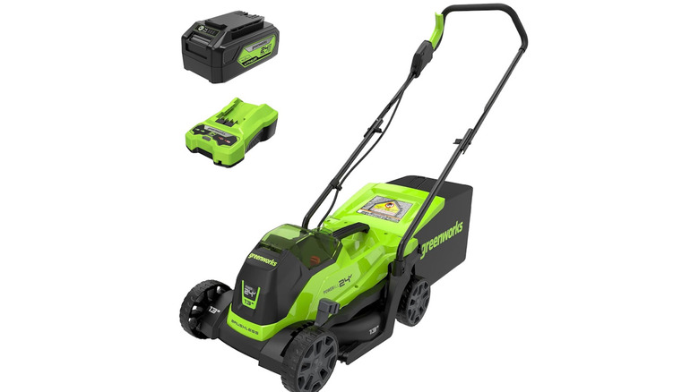 Green and black Greenworks 24V lawn mower with battery and charger on a white background