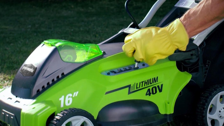 Greenworks lawn mower height being adjusted while being used on a lawn