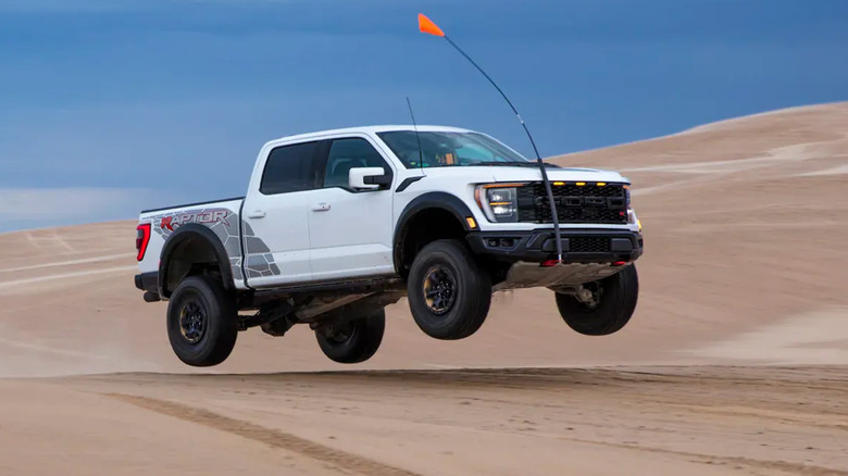 A Ford Raptor R jumping along sand dunes on a cloudy day