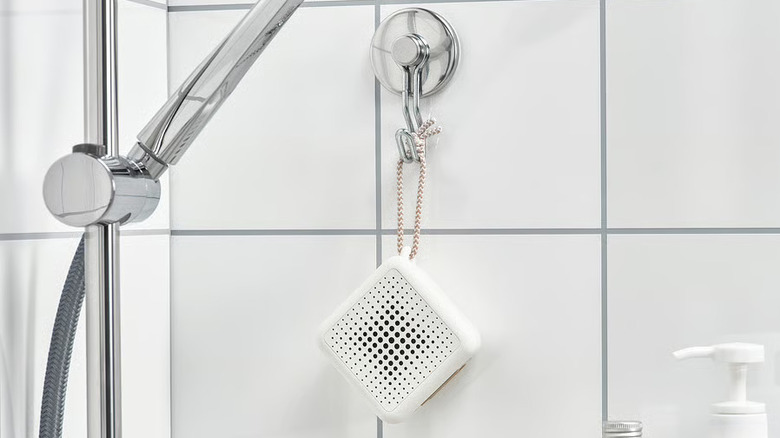 Portable Bluetooth speaker hanging from a shower handle in a bathroom