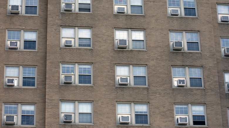 Rows of window-mounted air conditioners on a building exterior