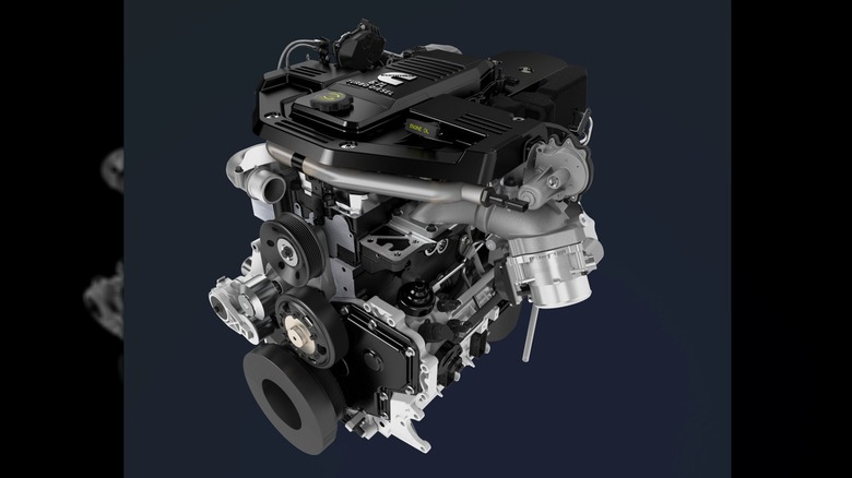 A modern Cummins 5.9L turbo diesel engine, featuring a clean, high-tech design with visible turbo components, belts, and pulleys on a plain background.