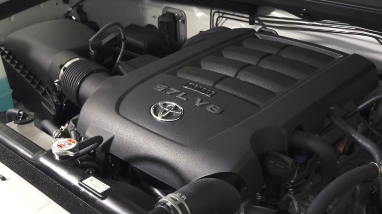 The engine bay of a Toyota pickup truck featuring the 5.7L i-Force V8 engine, with a black engine cover displaying the Toyota logo and engine designation.