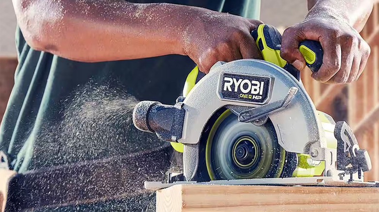 man using Ryobi circular saw to cut plank of wood