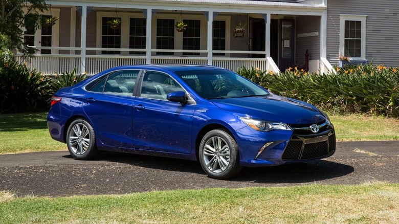 A blue Toyota Camry Hybrid on a driveway.