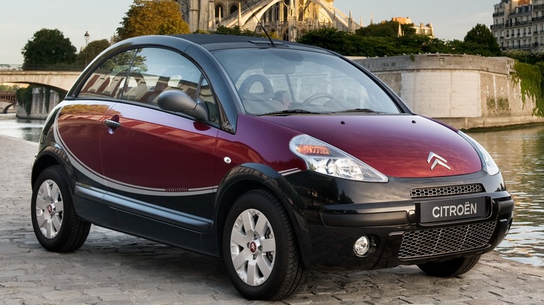 Red Citroën C3 Pluriel parked by a river with Notre Dame Cathedral in the background