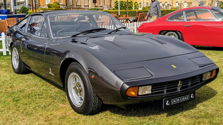 Black Ferrari 365 GTC/4 parked on grass at a car show