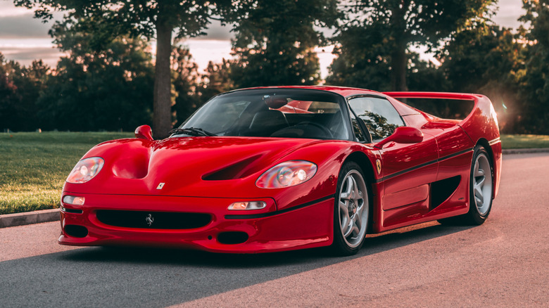 Red Ferrari F50 parked on a road at sunset