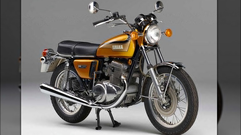 A vintage Yamaha TX750 in gold and chrome with classic round headlights and a twin-cylinder engine.