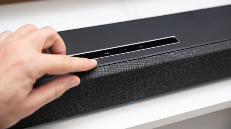 person pressing button on soundbar