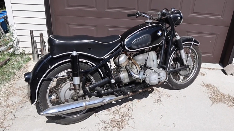 A black BMW R69S parked outside a garage.