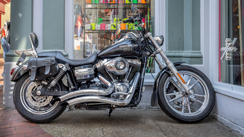A grey and silver Harley Davidson Super Glide motorcycle, side view visible with lots of chrome bits