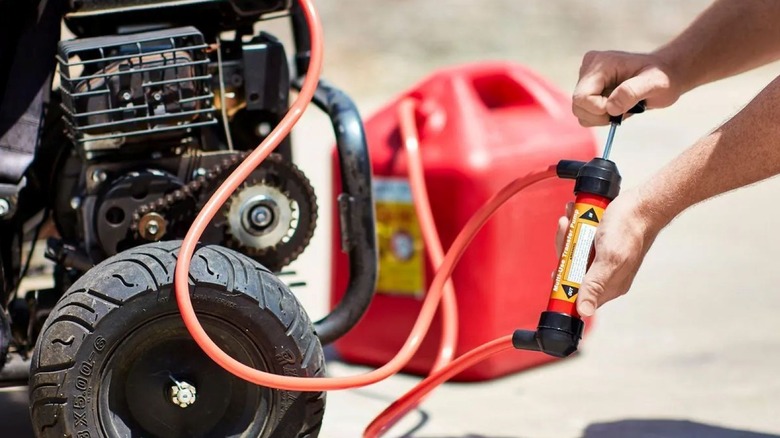 person using hand pump to transfer fuel