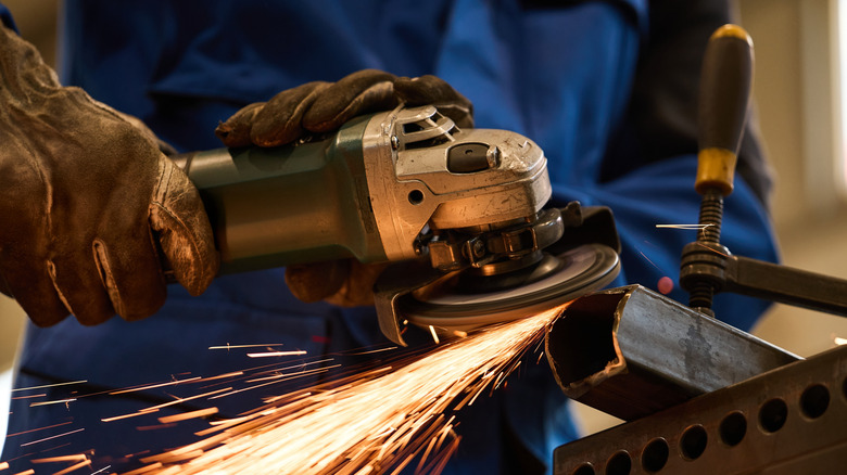 Aa technician working an angle grinder to cut a steel bar