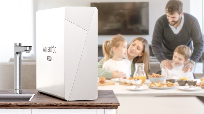 White Waterdrop Filter X12 system on kitchen counter with family eating dinner in background