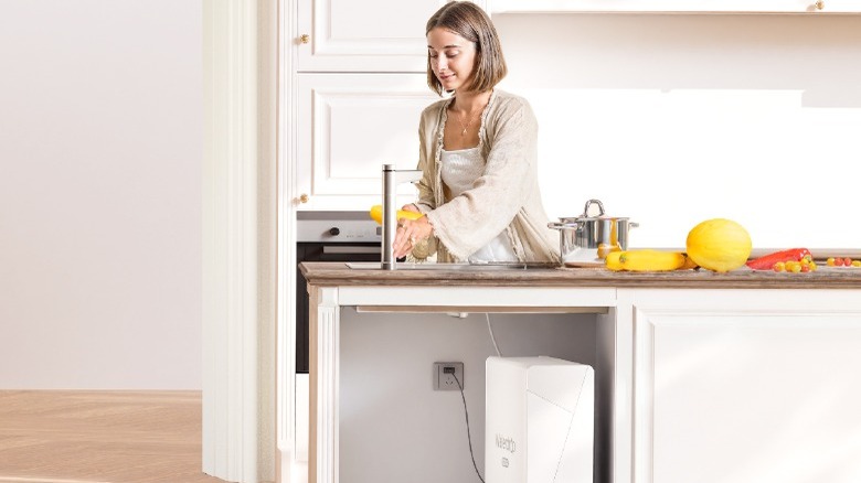 Woman washing vegetables in sink with Waterdrop Filter RO system below counter