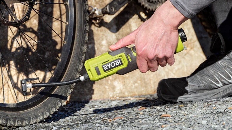 Person inflating tire with Ryobi inflator