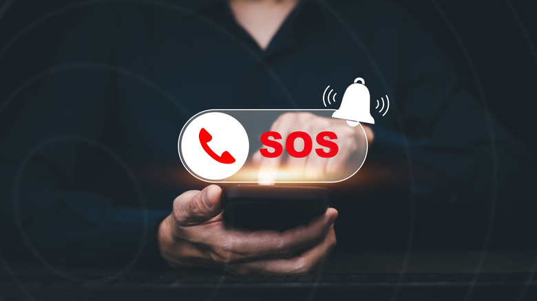 Hand touching a smartphone with an SOS and bell symbol projected above