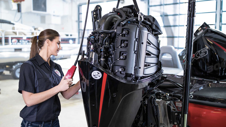 Photo of a Bass Pro Shops technician working on an outboard boat motor.