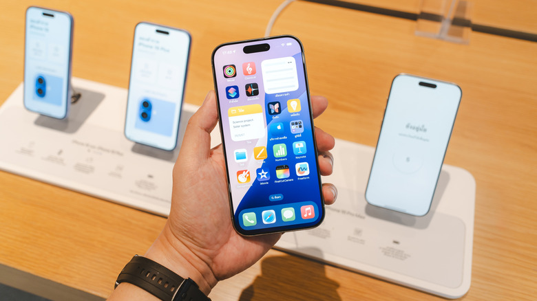 Person holding iPhone in front of Apple Store display