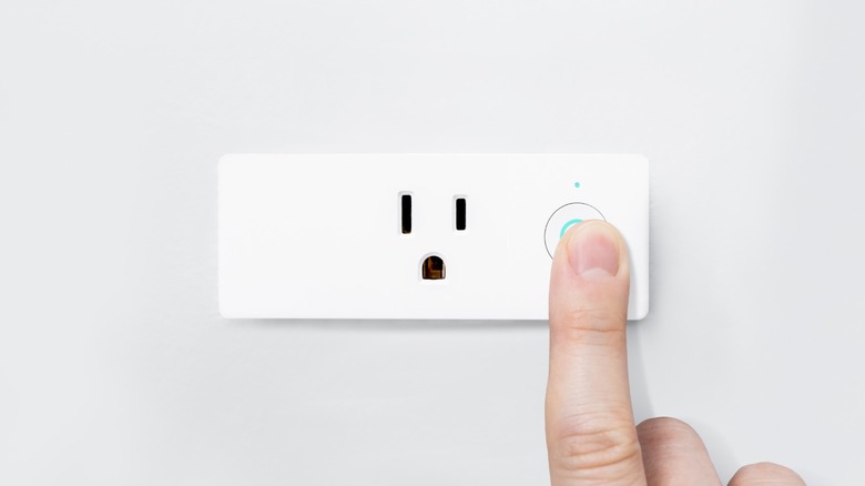 a person pressing the power button on a smart plug
