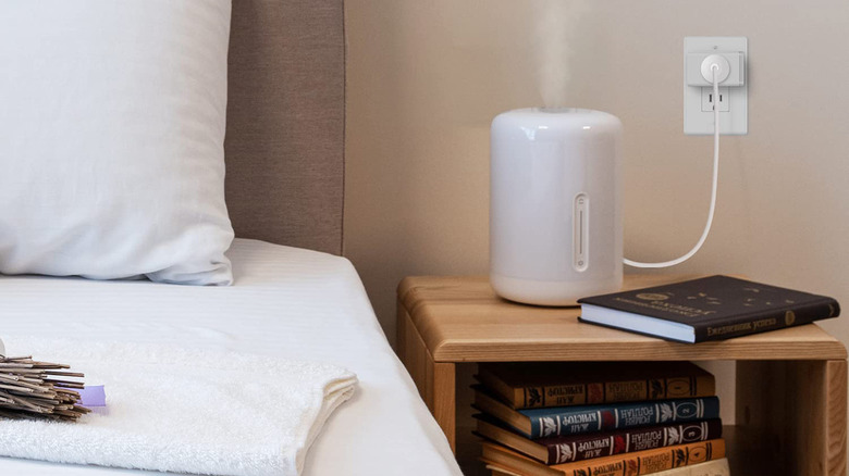 A humidifier on a nightstand connected to a smart plug