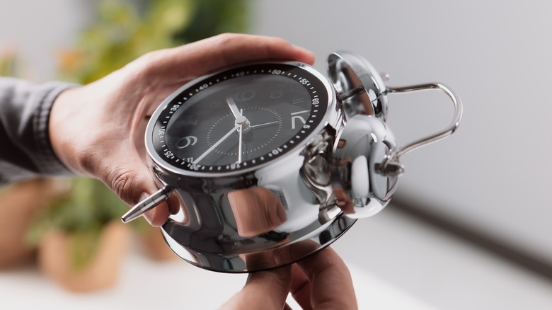hand setting an alarm clock