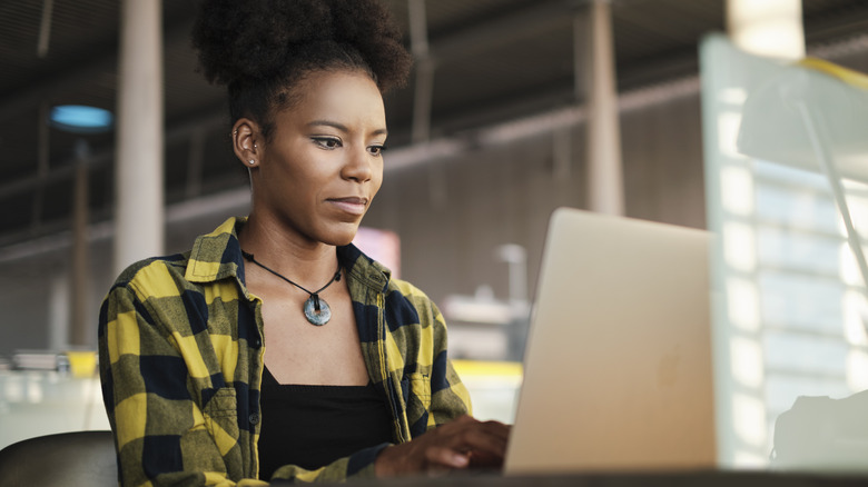 College student writing essay on laptop