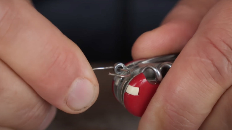 man using eyelet to bend wire