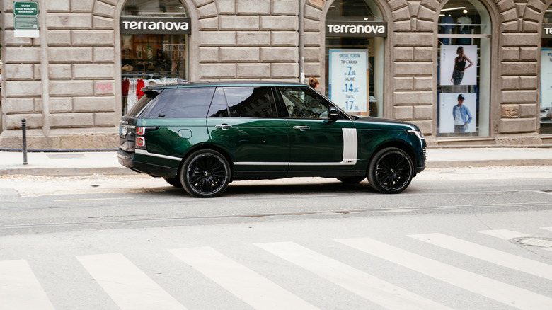 An emerald-green Land Rover Range Rover photographed against a grey brick wall.