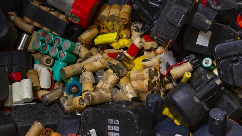 A stack of old batteries of many kinds, including AA and power tool batteries.