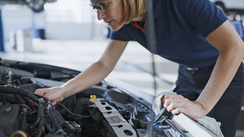 A person inspecting a car's engine bay