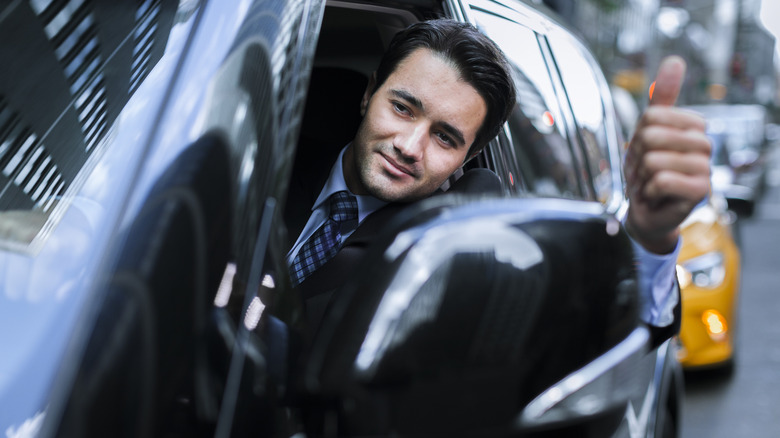 A driver leaning out of his window with thumbs up