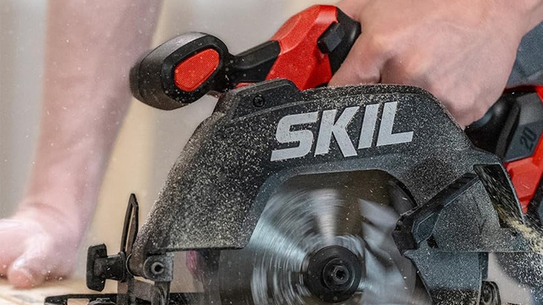 Skil Cordless saw being used to cut wood held by a person