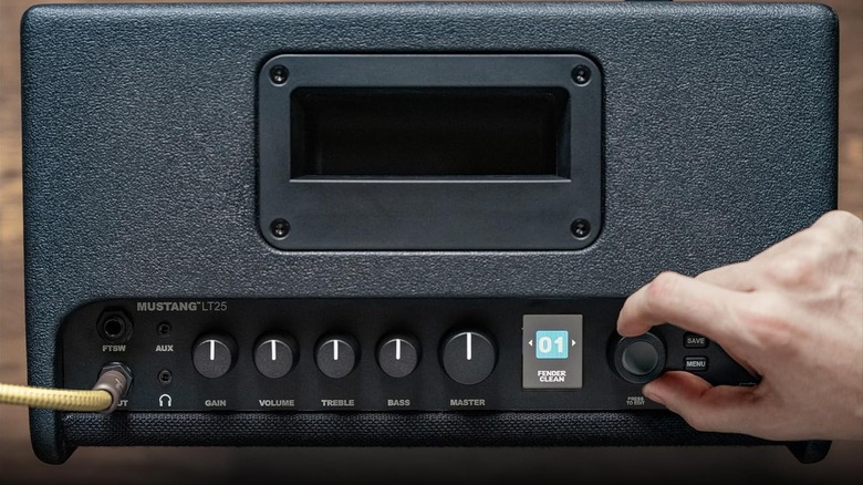 A hand messing with the pots on an amp.