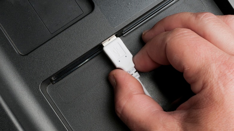 Hand plugs a white usb cable to a smart TV