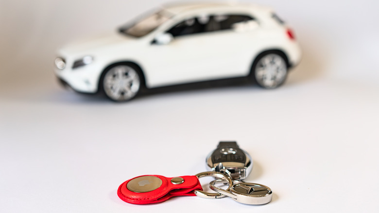 AirTag attached to keys lying on white table with blurry toy car in the background