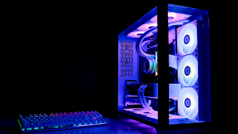 A computer in a transparent case in a dark room illuminated by purple LED fans.