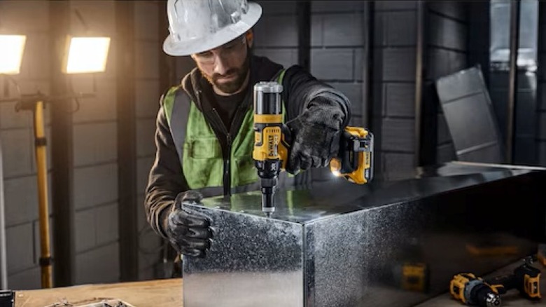 person using rivet gun on section of HVAC vent