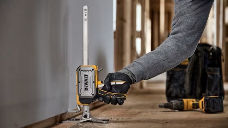person using construction jack to lift drywall panel