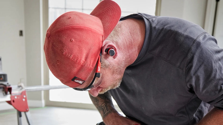 Worker using Milwaukee jobsite ear buds in workshop