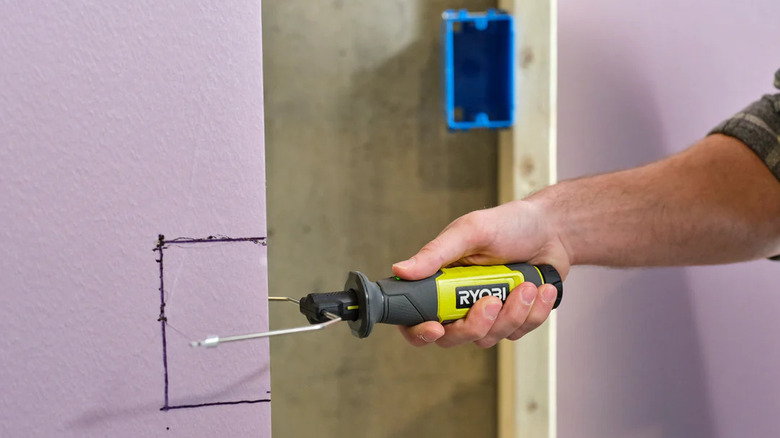 person using foam cutter on board insulation