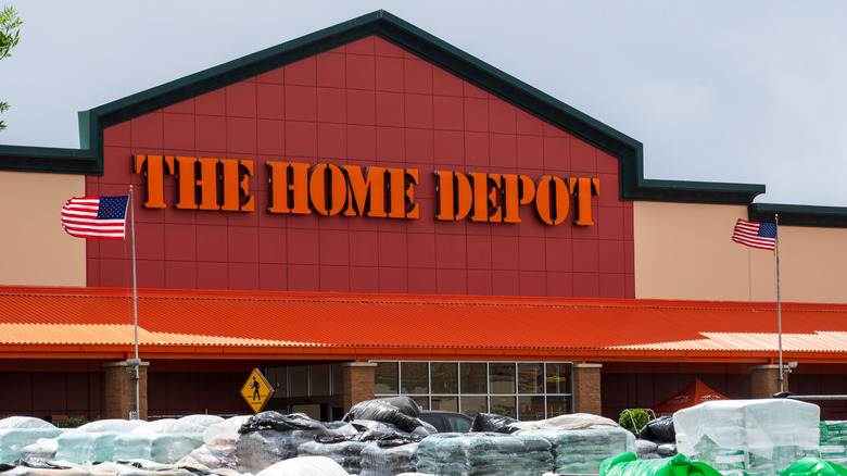 A Home Depot storefront with pallettes of lawn care products in foreground