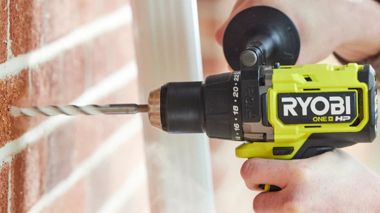 person using drill on brick wall