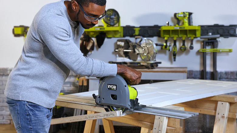 person using a track saw on a door