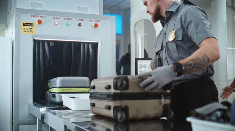 Security officer scans cases and property at airport.