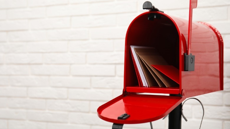 An open red mailbox with letters inside