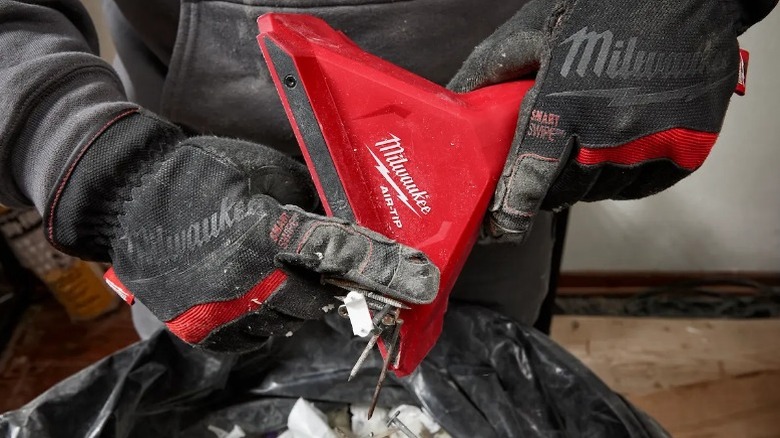 Person scraping screws and nails from Milwaukee Air-Tip 2 ½-inch Magnetic Utility Nozzle