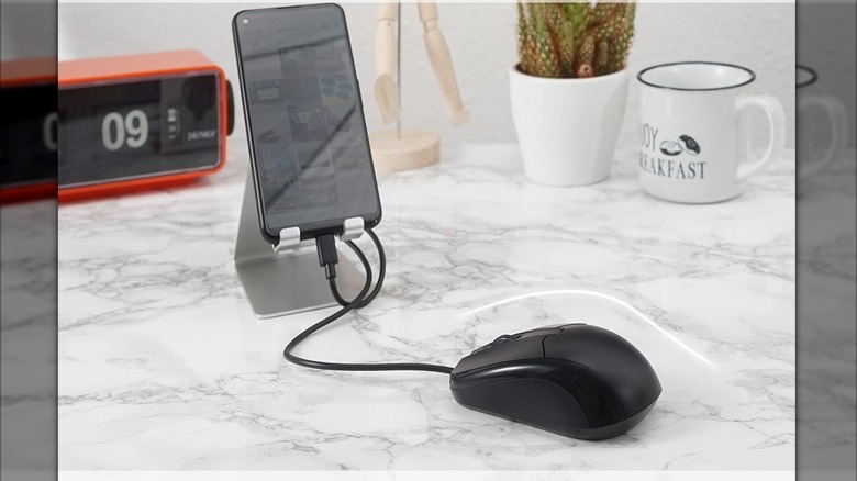 A mouse connected to an Android smartphone on a marble table.
