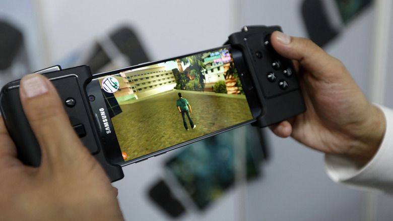 A person playing GTA Vice City on a Samsung phone with a mobile gaming controller